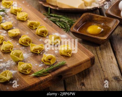 Homemade dumplings on a cutting board are waiting to be cooked. Ingredients on a wooden background. Recipes for home and restaurant cuisine. Culinary Stock Photo