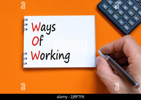 WOW ways of working symbol. Concept words WOW ways of working on white note on a beautiful orange background. Businessman hand. Black calculator. Busi Stock Photo