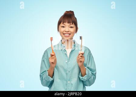 asian woman with wooden and plastic toothbrushes Stock Photo