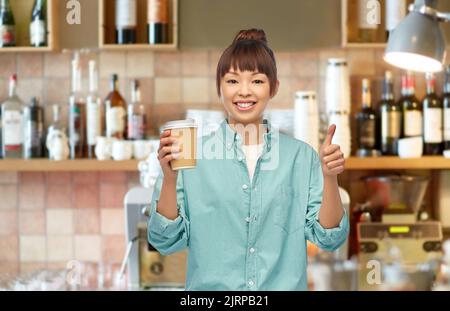 asian woman with coffee showing thumbs up at bar Stock Photo