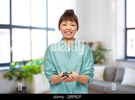 smiling young asian woman with alkaline batteries Stock Photo