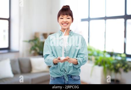 smiling young asian woman with toy wind turbine Stock Photo