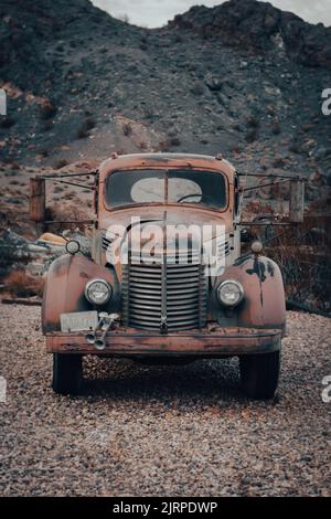 An old rusty truck is parked in a field of grass. The truck is ...