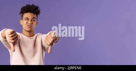 Close-up portrait of disappointed, unimpressed young hispanic man with dreads, grimacing skeptical, judging something bad, watched awful boring movie Stock Photo