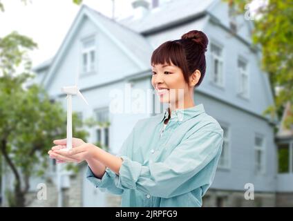 smiling young asian woman with toy wind turbine Stock Photo