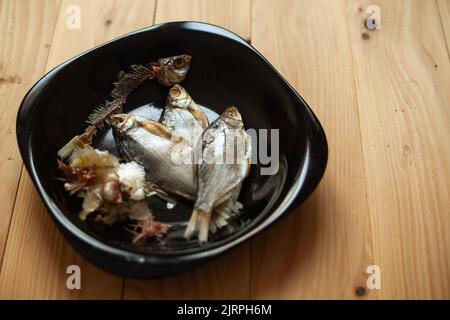 Dried salted fish on a black plate. Dried fish for beer. Stock Photo