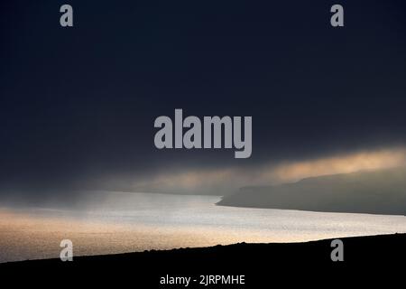 Cloudy sunset sky over sea and hills Stock Photo