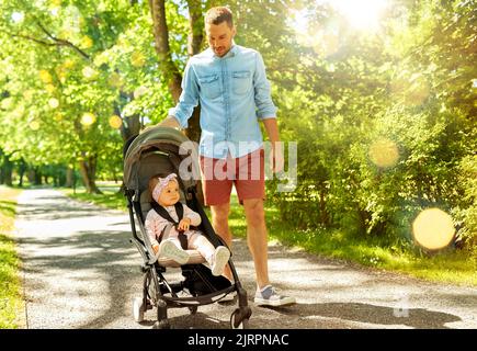 happy father with child in stroller at summer park Stock Photo