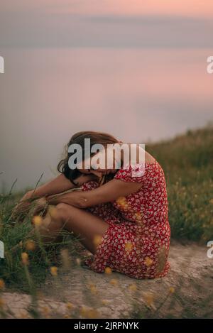 portrait girl in summer on mountain with her head bowed on her knees Stock Photo