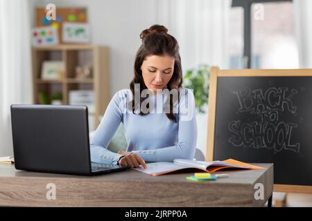 teacher with laptop and notebook working from home Stock Photo