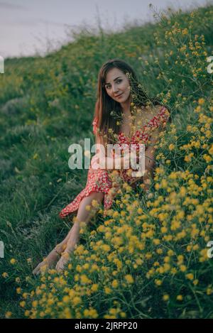 portrait of a girl in the summer on the grass cut yellow wildflowers Stock Photo