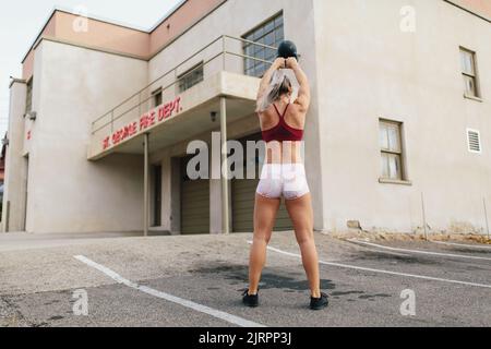 Young blonde woman doing kettlebell swing in front of old fire s Stock Photo
