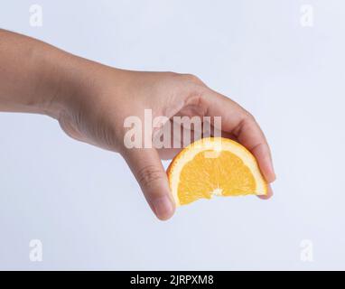 hand holding fresh raw citrus. hand squeezing orange fruit sliced on white background. Stock Photo