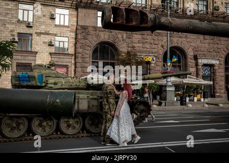 A Ukrainian soldier and his girlfriend stand next to a destroyed Russian tank in Kyiv. As dedicated to the upcoming Independence Day of Ukraine, and nearly 6 months after the full-scale invasion of Ukraine on February 24, the country's capital Kyiv held an exhibition on the main street of Khreschaytk Street showing multiple destroyed military equipment, tanks and weapons from The Armed Forces of The Russian Federation (AFRF).As the Russian full invasion of Ukraine started on February 24, the war has killed numerous civilians and soldiers, nearly 9000 Ukrainian military personnel have been kil Stock Photo