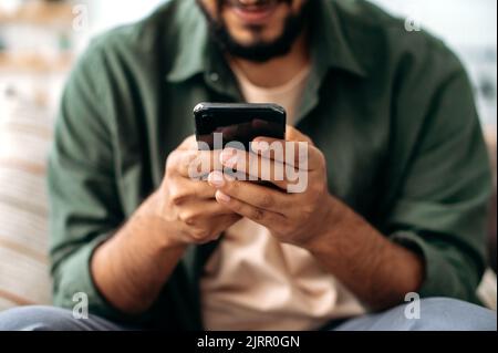 Close-up of a smartphone in a male hands. The concept of online messaging, social media communication, browsing the internet, websites, reading news. Wireless technologies, gadgets Stock Photo