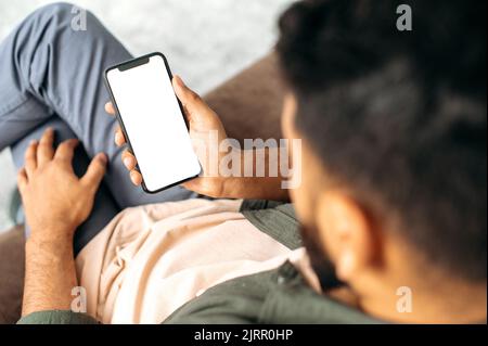 Top view. Mock-up. Gadgets and technologies concept. Modern smartphone in a male hand, with a blank white mockup screen for presentations, advertising, your text Stock Photo