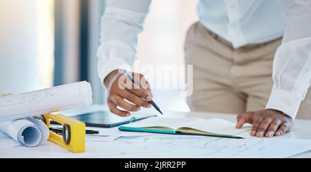 Architect, writing and planning with a business man drawing in a notebook with a blueprint and plan on a table in his office. Construction, engineer Stock Photo
