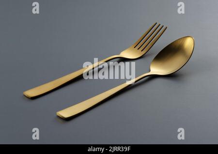 Gold knives and spoons set against a black background. Beautiful gold cutlery. Stock Photo