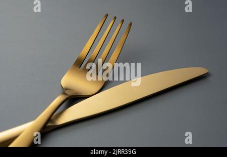 Gold knives and forks set against a black background. Beautiful gold cutlery. Close-up. Stock Photo