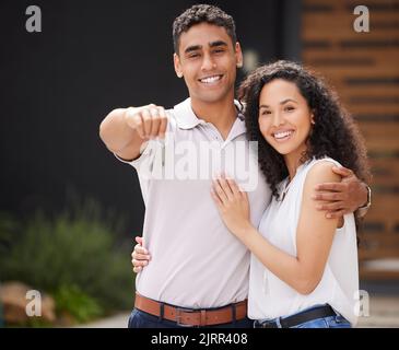 Happy couple with key to new home together, buying property as married man and woman and moving into real estate house. Portrait of people giving hug Stock Photo