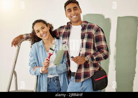 Painting, love and home with a couple doing DIY, renovation and house remodel with a paintbrush and roller. Domestic relationship and teamwork with a Stock Photo