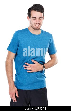 My stomach is killing me. of a young man suffering from indigestion against a white background. Stock Photo