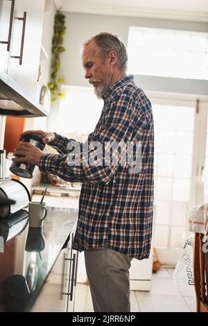 Time to start the day with a great cup of coffee. a focused senior man making himself a cup of coffee in the kitchen at home. Stock Photo