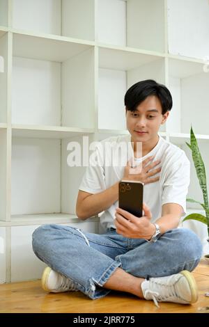 Portrait, Handsome young Asian man using smartphone, talking with his friends on a video call through his smartphone. Stock Photo