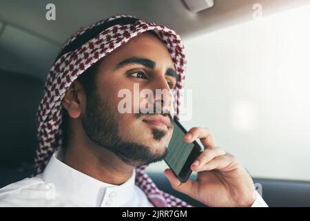 The right contacts will take you further. a young muslim businessman using his phone while traveling in a car. Stock Photo