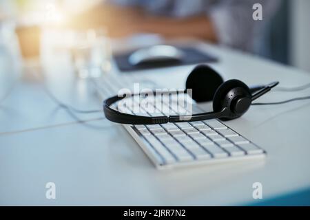 Your call is on hold. Closeup shot of a headset lying on a keyboard in an office. Stock Photo