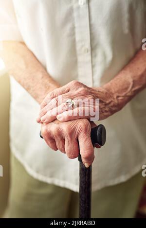 Moving around with a little help from her cane. an elderly woman holding onto a cane. Stock Photo