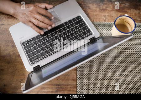 A Man Working from Home in Front of Laptop with a Cup of Coffee Stock Photo