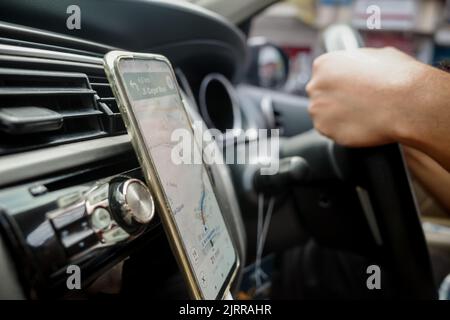 Man driving car using online map on smartphone. Hands on steering wheel Stock Photo