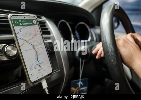 Man Driving Car Using Online Map on Smartphone for Direction Hands on Steering Wheel Stock Photo