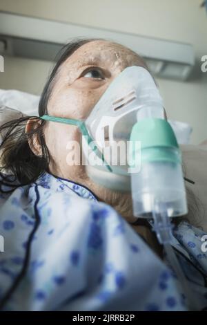 Southeast Asian female senior patient being treatment in hospital using nebulizer Stock Photo