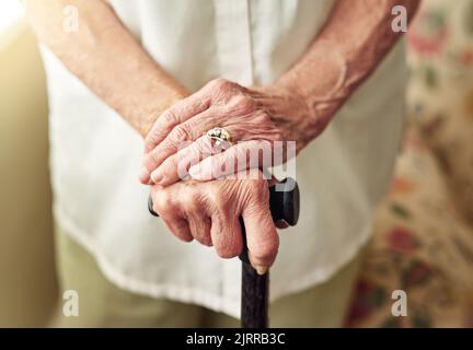 Improving mobility with a walking stick. an elderly woman holding onto a cane. Stock Photo