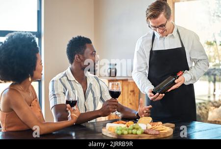 Couple doing wine tasting at a vineyard, eating food on romantic vacation and drinking alcohol at farm together. Happy African couple getting snacks Stock Photo