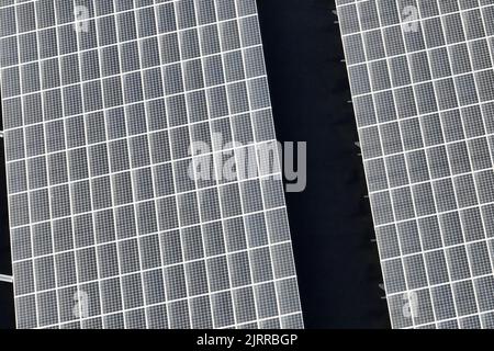 Aerial view of solar power plant with blue photovoltaic panels mounted on industrial building roof for producing green ecological electricity Stock Photo