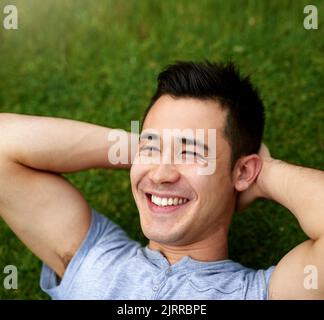 Time to chill out and enjoy the weekend. a handsome young man relaxing on the grass outdoors. Stock Photo