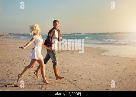 Playfully in love. an affectionate young couple enjoying their time on the beach. Stock Photo