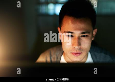 Working late into the night. a handsome young male programmer working late in his office. Stock Photo
