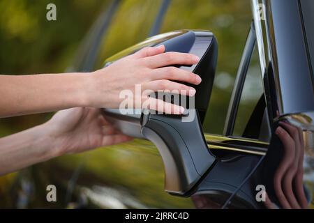 Driver hands adjusting side view mirror of a car Stock Photo