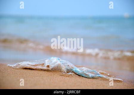 Left behind plastic bag garbage on sandy beach. Empty used dirty litter on sea shore. Environmental pollution. Ecological problem Stock Photo