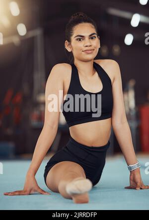 Dance or gymnastics stretching, sports health exercise and split training before a fitness workout. Portrait of a young woman gymnast or dancer before Stock Photo