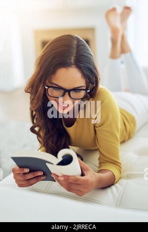 Using my free time wisely and productively. a young woman reading a book while relaxing at home. Stock Photo