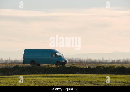 Small cargo van driving on highway hauling goods. Delivery transportation and logistics concept Stock Photo