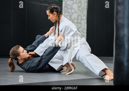 Mma, karate and jiu jitsu with two female athletes practicing, training and sparring in fight class. Healthy, fit and active women in gi or uniform Stock Photo