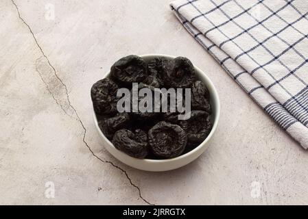 Dried plums in a white bowl isolated on marble background Stock Photo