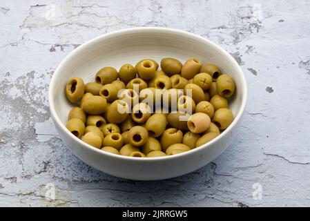 Pitted green olives in a white ceramic bowl Stock Photo