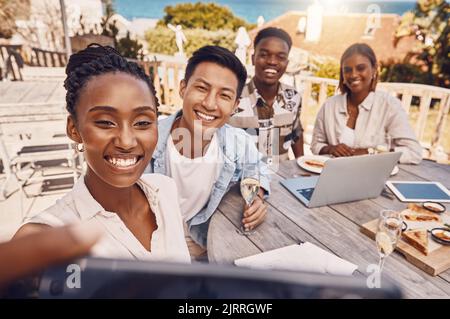 Group of business people taking a selfie at a restaurant having a lunch meeting outdoors in a city. Colleagues or friends take a picture or a photo Stock Photo